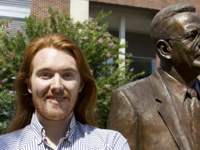 Rowan Music Performance major Jesse Panico next to the Henry Rowan statue