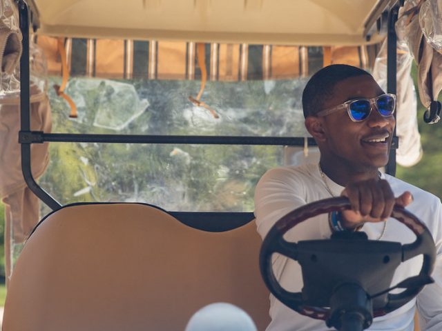 Silas sits in the driver's seat of a Rowan golf cart with one hand on the wheel, looking off camera