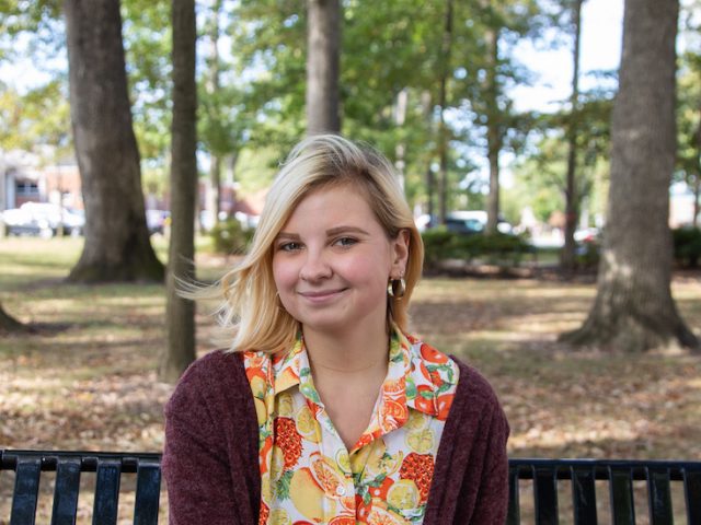 Grace Van Cleef posing on a bench on Rowan University's campus.