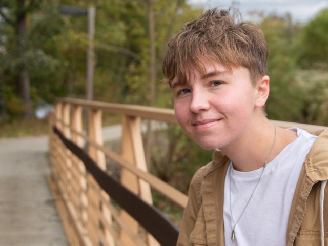 Rowan psychology major Caleb Jones stands in front of a footbridge on campus