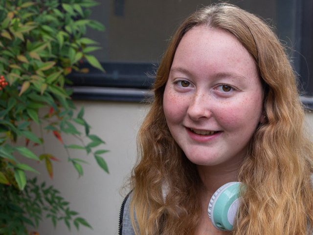 Freshman Public Relations major Rachel Rumsby sits on a bench outside on Rowan's campus.