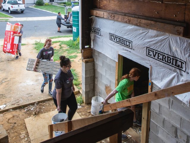 students moving construction equipment in a shell of a house