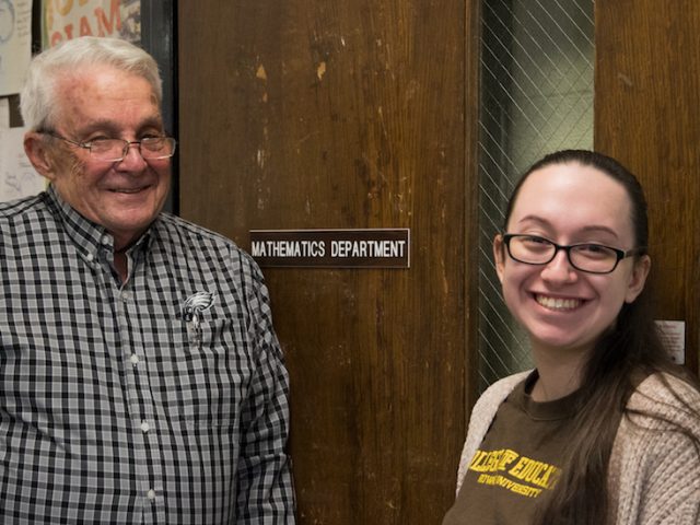 Adriana and Professor Smith smile in front of the Mathematics suite.