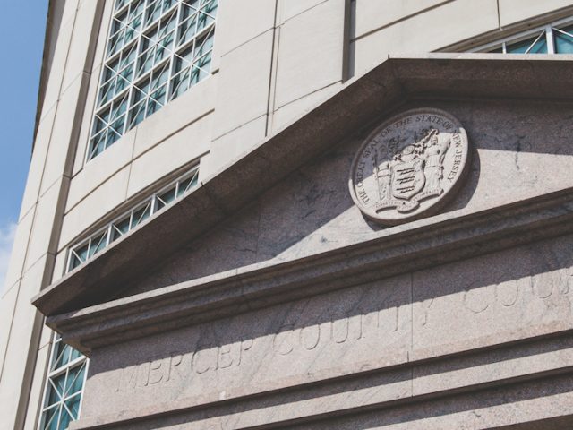 concrete facade of Mercer County Court House with flag in background