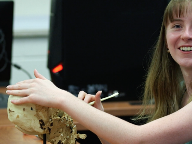 Emily carving a clay skull in a classroom.