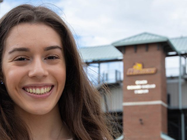 Kayla smiles and stands in front of Wackar Stadium