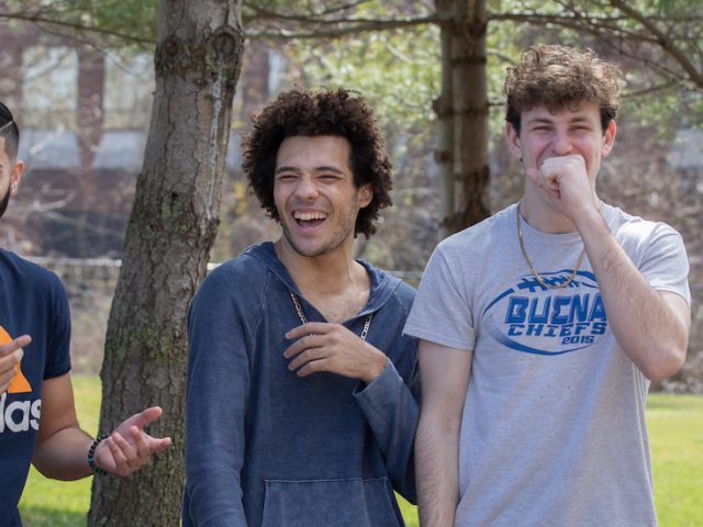 A candid photo of four male freshmen laughing together.