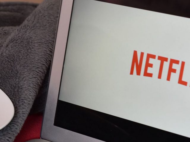 Laptop with the Netflix logo and a plate of snacks