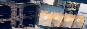 Bags at pizzeria lined up on a counter ready for pick up.