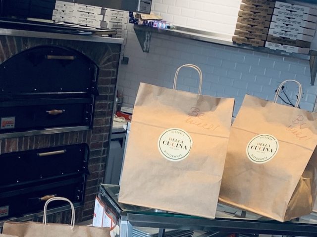 Bags at pizzeria lined up on a counter ready for pick up.