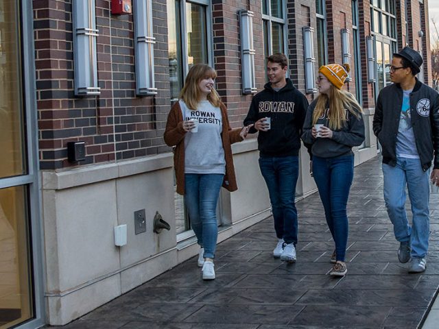 Christian walks with a group of students down Rowan Boulevard