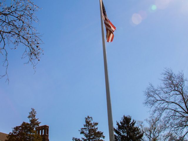 Bunce Hall, a flag, and the sun.