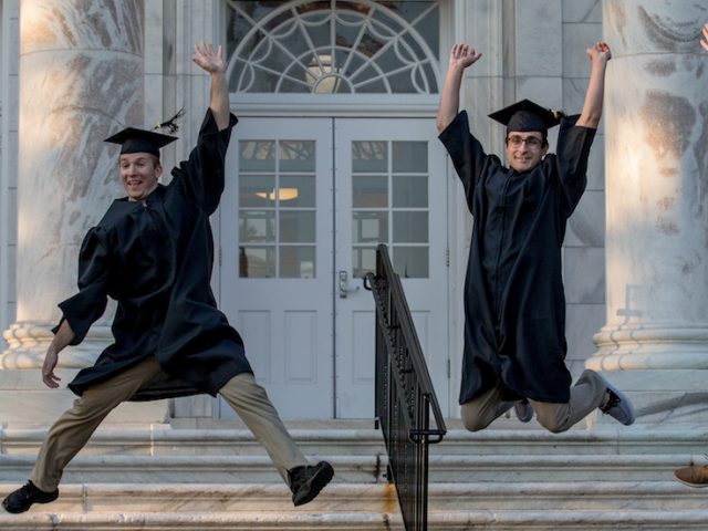 4 rowan grads jump in graduation attire.