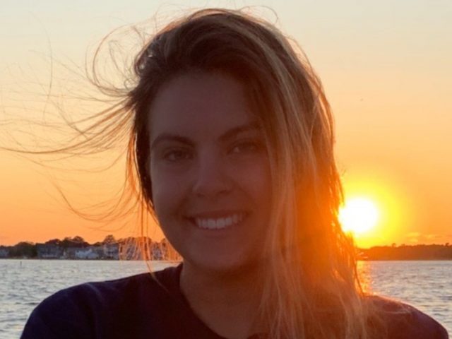 Taylor Melillo in front of a sunset on the water.