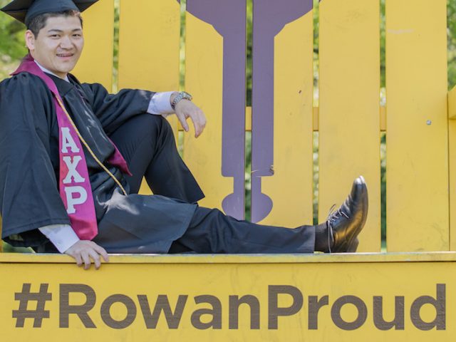 Health promotion and wellness management major Eric Chen posing on the Rowan Proud yellow chair.