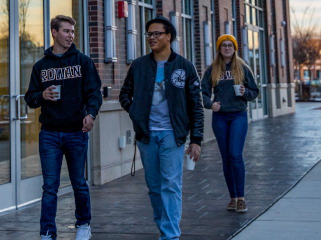 Christian walks down Rowan Boulevard with two other students