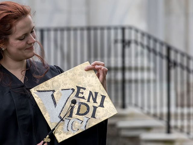 Sarah Transue holds her decorated cap in front of Bunce Hall