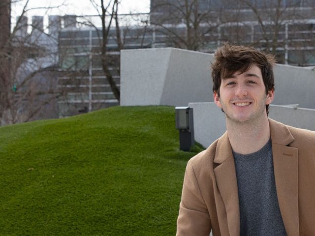 James Milward sits on the green next to Wilson Hall