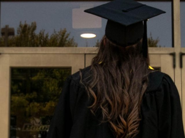 Megan poses in front of the Rec Center in her graduation cap and gown.