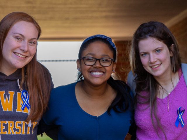 Five Rowan students posing and smiling outside on campus