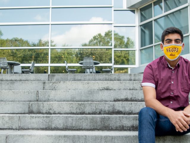 Bhavik sits on the steps of Engineering Hall wearing a mask.