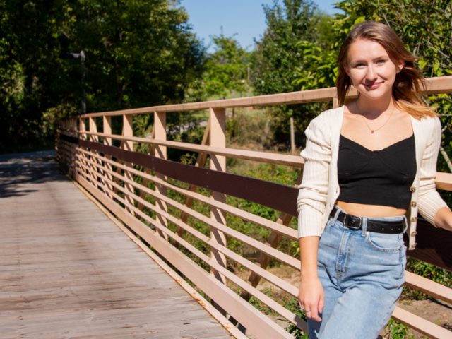 Angela stands on a bridge on campus.