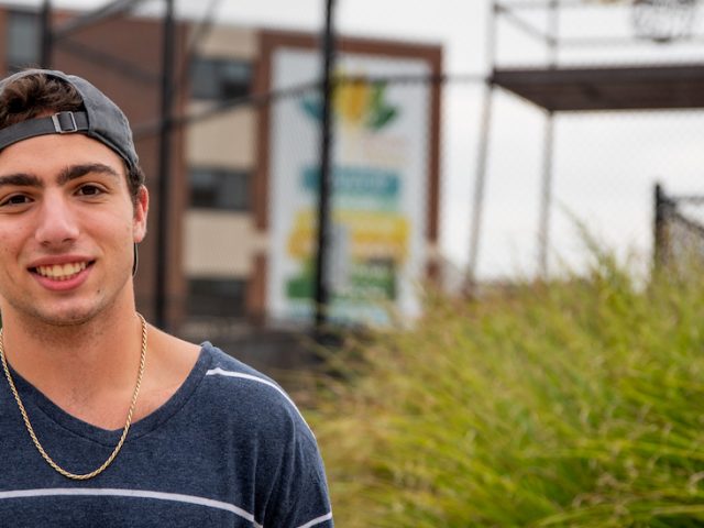 Spencer wearing a hat and standing outside on campus.