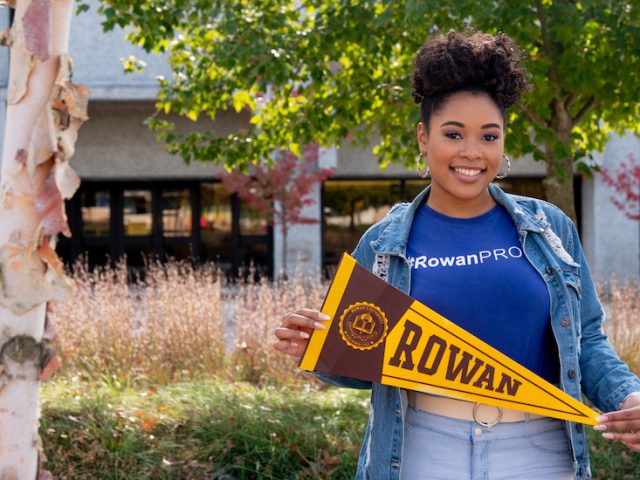 College of Education student Cheyenne holds a pennant on campus.