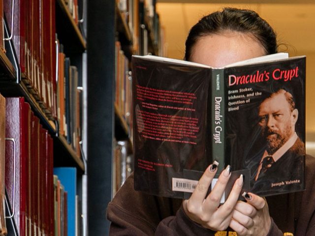 Student reads a book in the stacks of Campbell Library.