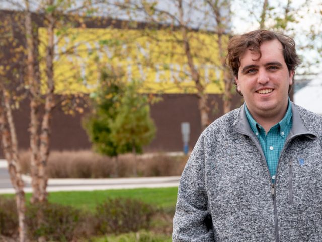 Connor stands in front of the student center.