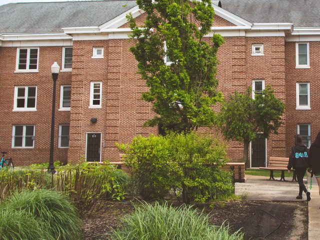 People walk in front of a residence hall.