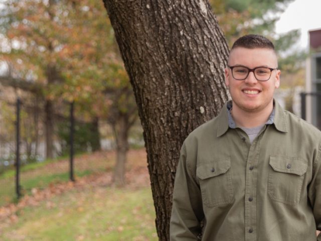 Brett poses next to a tree.