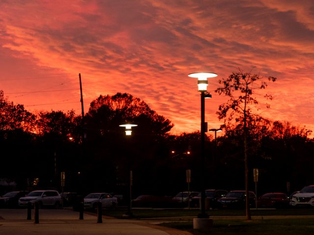 Sunset at Rowan with stark red sky against black silouette of buildings and trees.