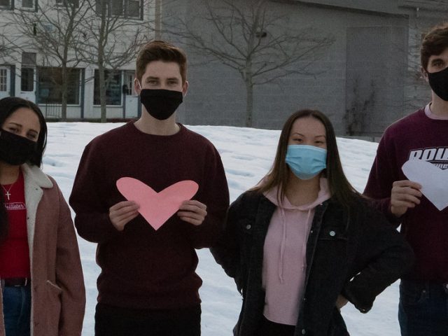 Rowan students hold hearts along Rowan Boulevard park area.