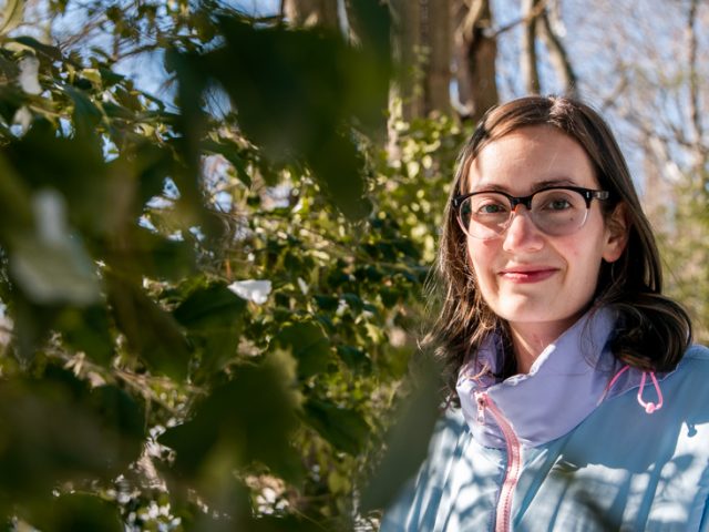 JoAnna standing in between a a tree.