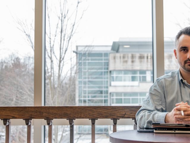 Jordan sitting at a table in Wilson with a window behind him.