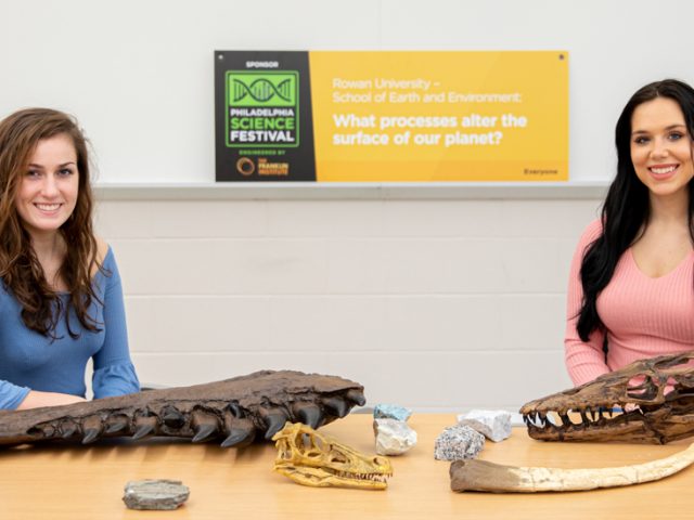 Kayla and Jude sitting down with fossils on a table in front of them.