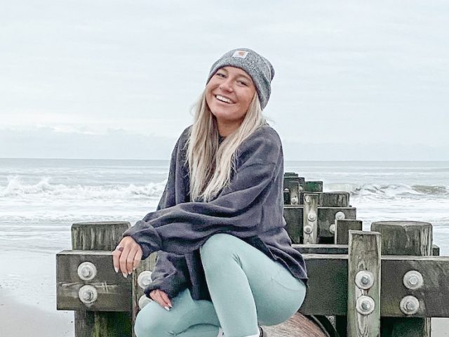 Autumn smiles, wears a hat at the beach.