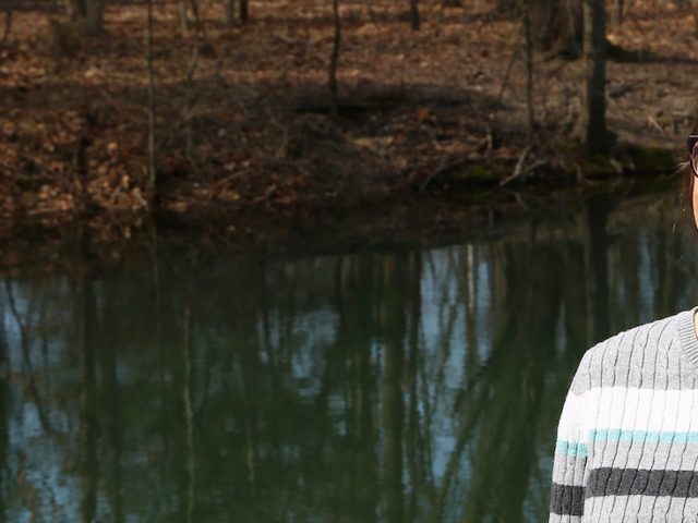 Allison stands and smiles next to a waterway on campus.