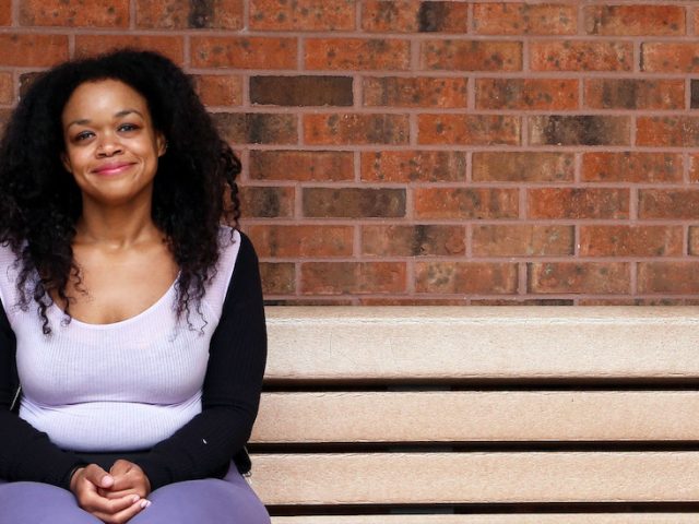 Melinda sits on a bench on campus.