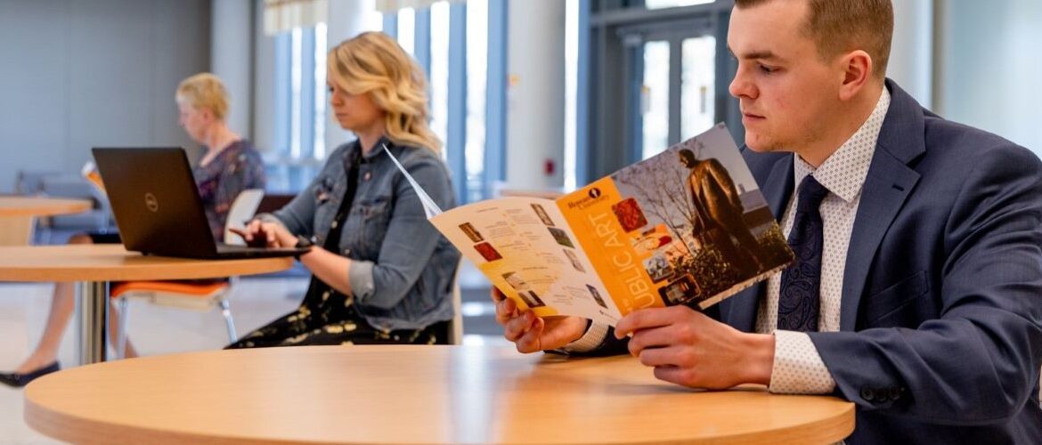 Student reading a Rowan flyer at the Business Hall