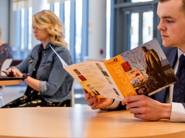 Student reading a Rowan flyer at the Business Hall