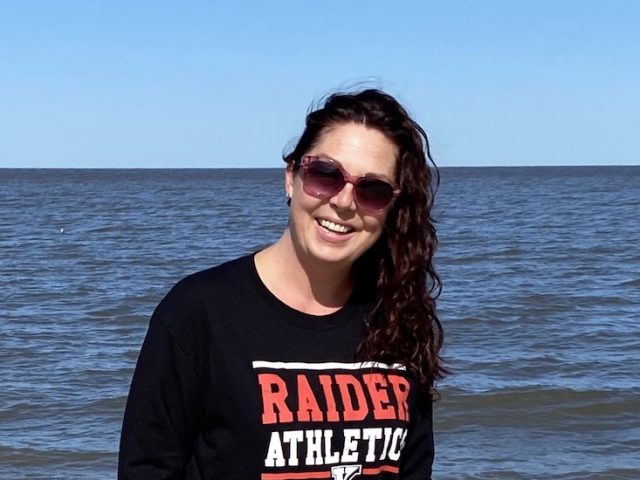 A photo of Heather outside at the beach wearing sunglasses.