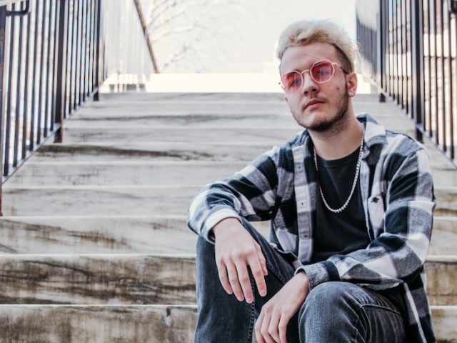 Dom sits on marble steps at Bunce Hall wearing black-and-white plaid.