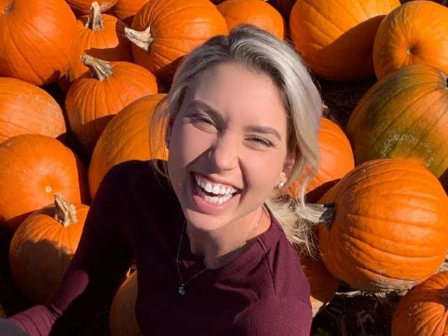 Outdoor photo of Sara smiling in a pumpkin patch.