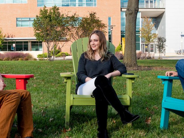 Alexandra sits and talks with friends on campus.