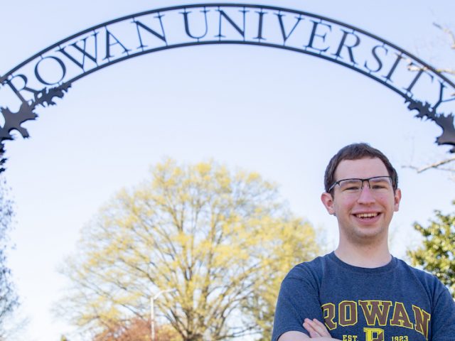 Kevin stands in front of the Rowan arch in a Rowan t-shirt.