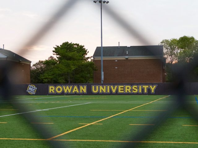 An athletic field as seen through a fence on campus.