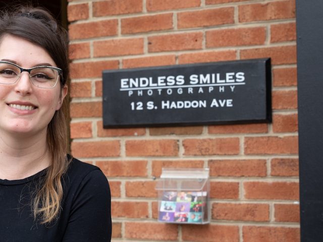 Gabi stands in front of the Endless Smiles Photography Sign