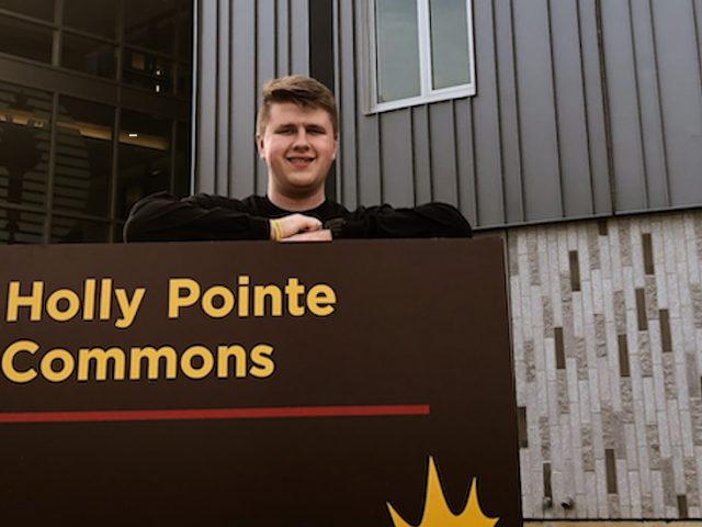 Mitch poses at the Holly Pointe Commons sign.